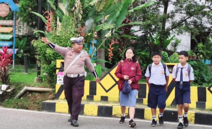 Petugas Satlantas Polres Tana Toraja membantu menyeberangkan siswa di depan sekolah saat kegiatan Strong Point pagi hari, Selasa (22/4/2025) (Foto: Humas).