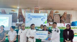 Bupati Toraja Utara, Frederik Viktor Palimbong didampingi oleh Kepala Dinas Pemberdayaan Masyarakat dan Lembang (DPML), dan Kepala BPJS Ketenagakerjaan Cabang Tana Toraja Makale, Sulis Indrayani yang menyerahkan santunan kematian secara simbolis kepada ahli waris saat kegiatan sosialisasi manfaat program jaminan sosial ketenagakerjaan kepada ekosistem lembang se-Kabupaten Toraja Utara, di Toraja hotel Prince, Rabu, (07/05/25). (Dok. Zul/Gasingnews.com)