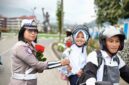 Anggota Satlantas Polres Tana Toraja yang memberikan bunga kepada salah satu anak sekolah, yang di bonceng, saat melintas di Plaza Kolam Makale, Tana Toraja, Rabu (23/07/25).