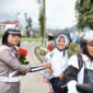 Anggota Satlantas Polres Tana Toraja yang memberikan bunga kepada salah satu anak sekolah, yang di bonceng, saat melintas di Plaza Kolam Makale, Tana Toraja, Rabu (23/07/25).