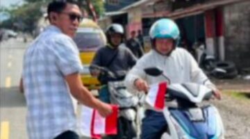 Kasat Intelkam Iptu Desi Salinding membagikan bendera Merah putih kepada pengendara penguna jalan, Rabu (6/8/2025) (Foto: Humas).